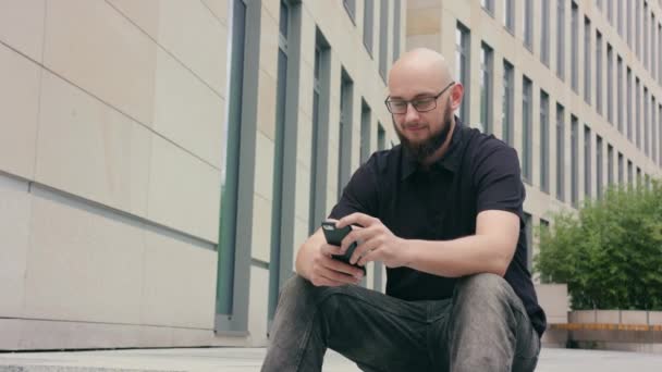 Man met baard dragen van een bril met behulp van een telefoon in de stad — Stockvideo