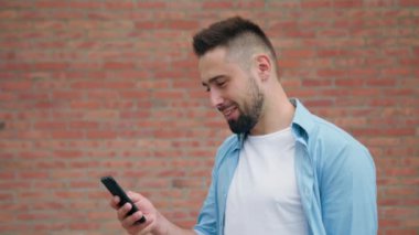 Sakallı bir tuğla duvara bir telefonu kullanarak