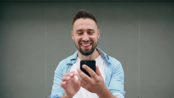 Άνδρας με γενειάδα χρησιμοποιώντας ένα τηλέφωνο σε ένα γκρίζο φόντο — Αρχείο Βίντεο