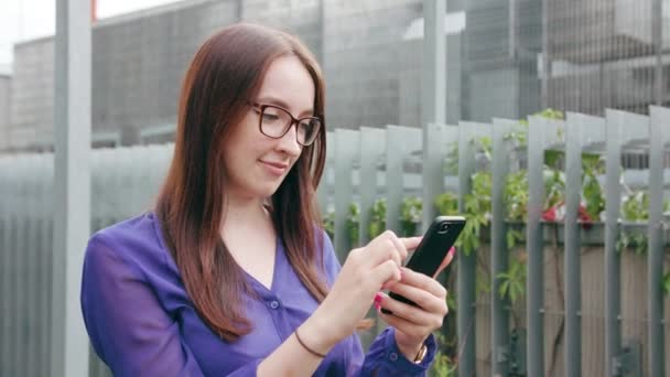 Brunette vrouw met behulp van een telefoon in de stad — Stockvideo