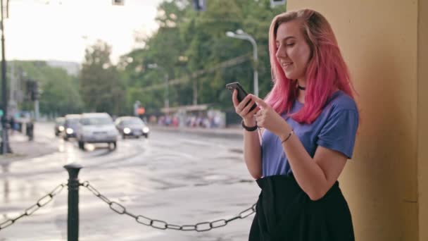 Kvinna med rosa hår använder en telefon i stan — Stockvideo