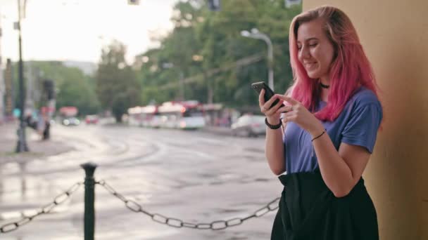 Kvinna med rosa hår använder en telefon i stan — Stockvideo
