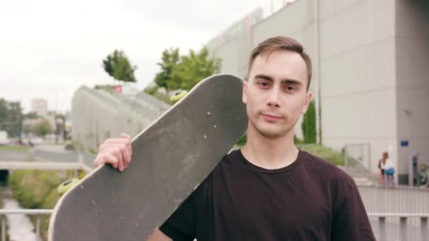 Un jeune homme avec une planche à roulettes en ville — Video