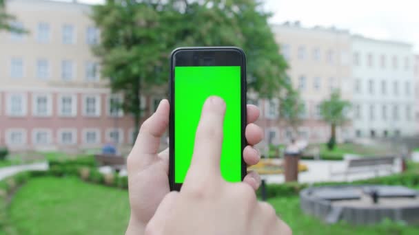 Een hand die een telefoon vasthoudt met een groen scherm — Stockvideo