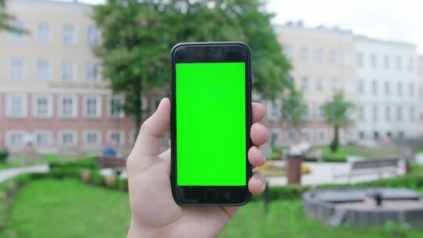 Een hand die een telefoon vasthoudt met een groen scherm — Stockvideo