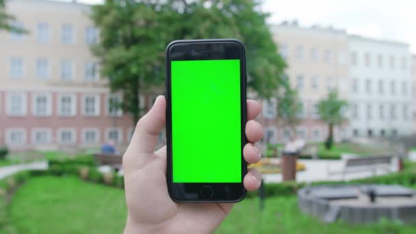 Een hand die een telefoon vasthoudt met een groen scherm — Stockvideo