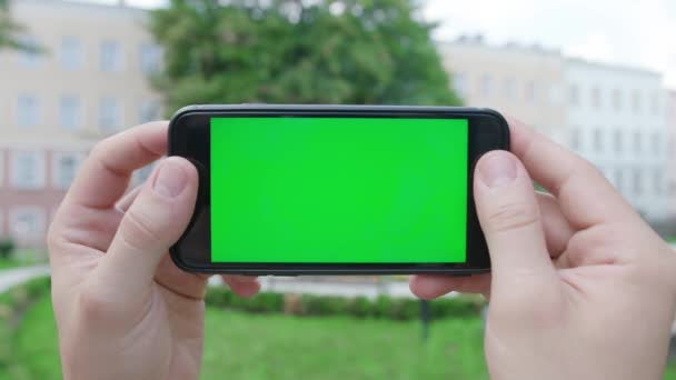 Mãos segurando um telefone com uma tela verde — Vídeo de Stock