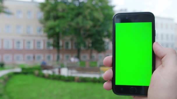 Een hand die een telefoon vasthoudt met een groen scherm — Stockvideo