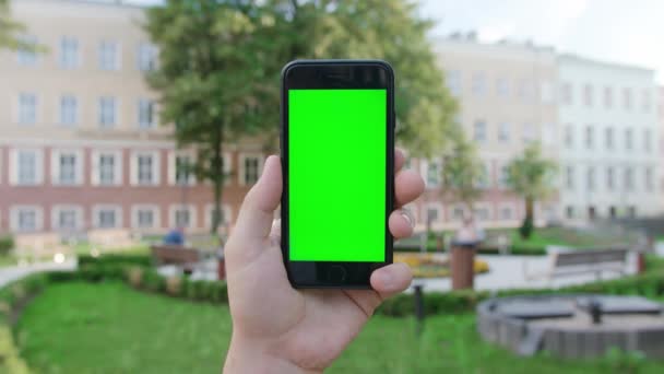 Ένα χέρι κρατώντας ένα τηλέφωνο με μια πράσινη οθόνη — Αρχείο Βίντεο
