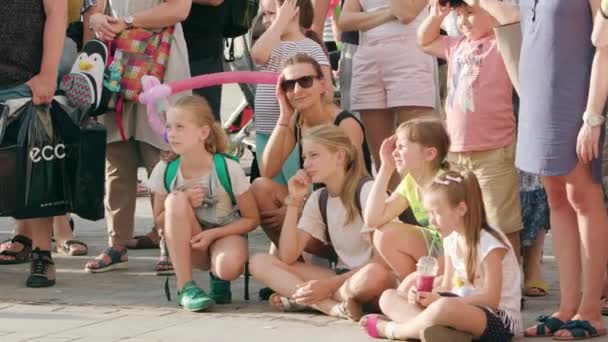 Una multitud de niños sentados en el suelo de la ciudad — Vídeo de stock