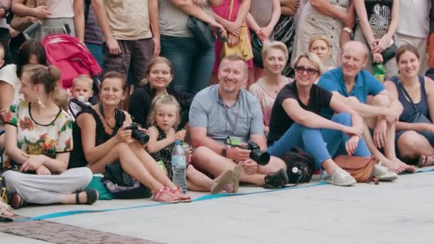 Толпа людей, сидящих на земле в городе — стоковое видео