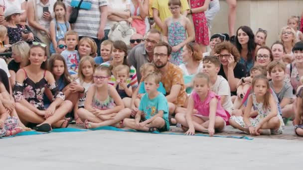 Толпа людей, сидящих на земле в городе — стоковое видео