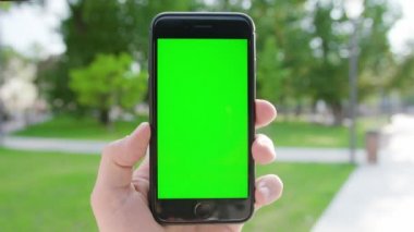 Lublin, Polonya - Temmuz 2018: Halka açık bir parkta yeşil ekranlı bir telefonu tutan bir el. Yakın plan çekim. Yumuşak odak