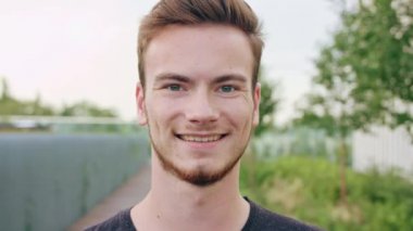 Kasabada gülümseyen sakallı kızıl saçlı adam.