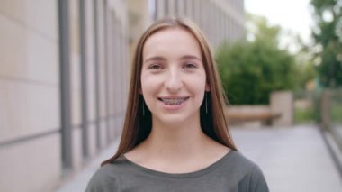 Dişlerini şehrin sokak üzerinde parantez giymiş bir mutlu gülümseyen kadın. Yakın çekim shot. Yumuşak odak