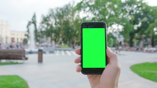 Una mano sosteniendo un teléfono con una pantalla verde — Vídeo de stock