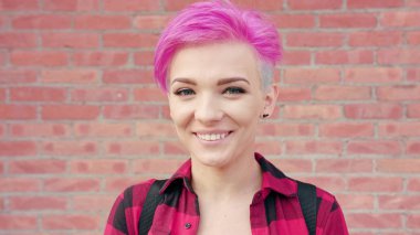 Duvara karşı pembe saçlı mutlu gülümseyen kadın