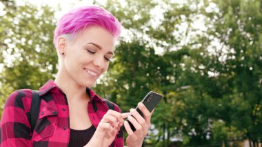 Kasabada bir telefonu kullanarak pembe kısa saçlı kadın