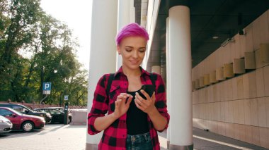 Kasabada bir telefonu kullanarak pembe kısa saçlı kadın