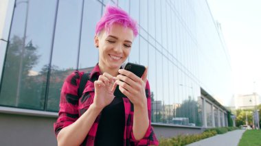 Kasabada bir telefonu kullanarak pembe kısa saçlı kadın