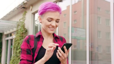 Kasabada bir telefonu kullanarak pembe kısa saçlı kadın