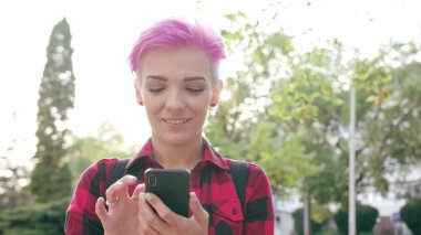 Kasabada bir telefonu kullanarak pembe kısa saçlı kadın