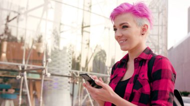 Kasabada bir telefonu kullanarak pembe kısa saçlı kadın