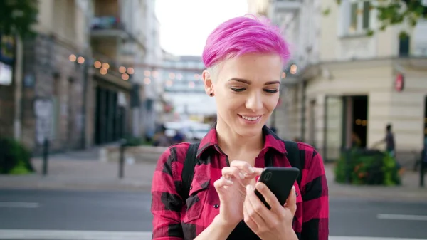 Женщина с короткими розовыми волосами с помощью телефона в городе — стоковое фото
