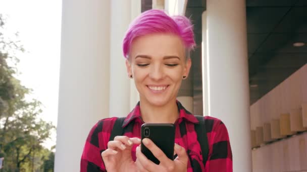 Femme aux cheveux courts roses utilisant un téléphone en ville — Video