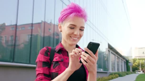 Mulher com cabelo curto rosa usando um telefone na cidade — Vídeo de Stock