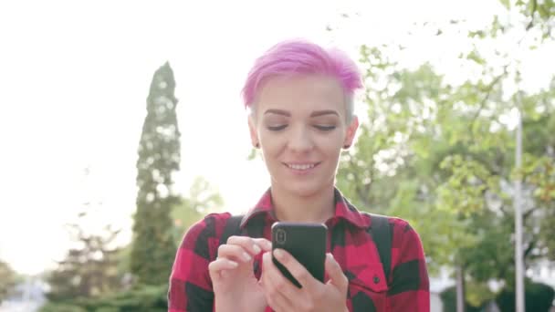 Mulher com cabelo curto rosa usando um telefone na cidade — Vídeo de Stock