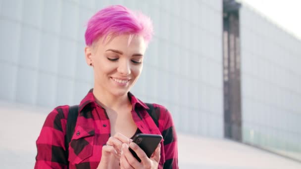 Frau mit pinkfarbenen kurzen Haaren telefoniert in der Stadt — Stockvideo