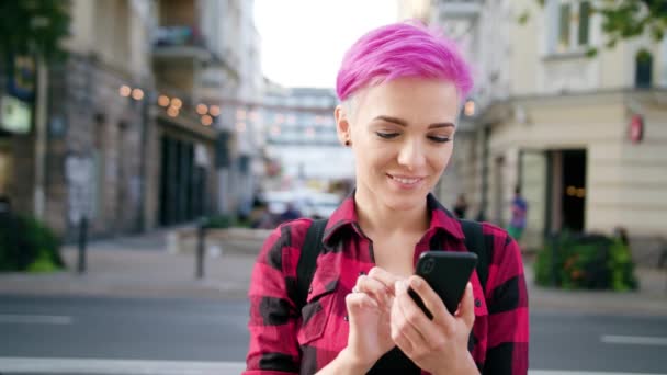 Kvinna med rosa kort hår använder en telefon i stan — Stockvideo