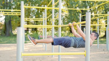 Kaslı adam yatay çubuğu egzersizleri yapıyor