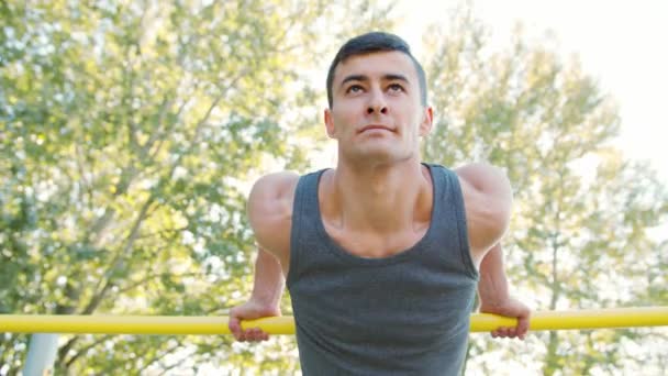 М'язистий чоловік робить вправи на горизонтальній панелі — стокове відео