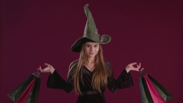 Mädchen im Halloween-Hexenkostüm mit Einkaufstaschen. — Stockvideo