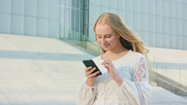 Młoda Blondynka Pani spaceru i korzystania z telefonu w mieście — Wideo stockowe