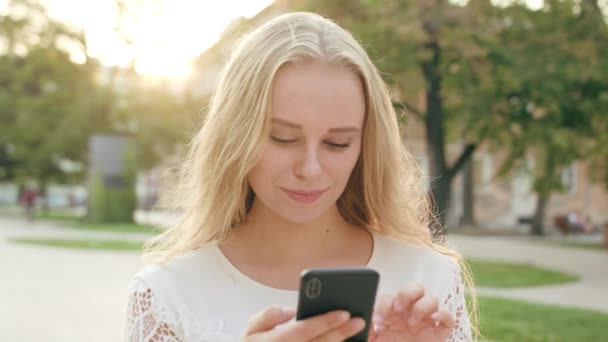 Ung blond dam med en telefon i stan — Stockvideo