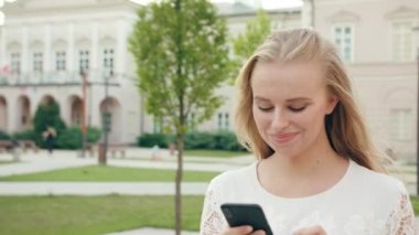 Genç sarışın Bayan yürüyüş ve şehirde bir telefon kullanma