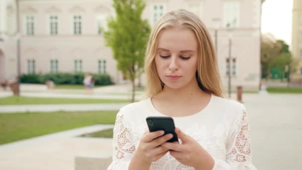 Mladá blondýnka dáma pomocí telefonu ve městě — Stock video