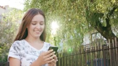 Bir şehirde yürürken telefonunuzun ve çekici bir genç bayan. Yakın çekim dolly vurdu. Yumuşak odak