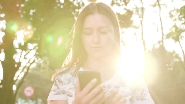 Giovane signora utilizzando un telefono in città mentre si cammina — Video Stock