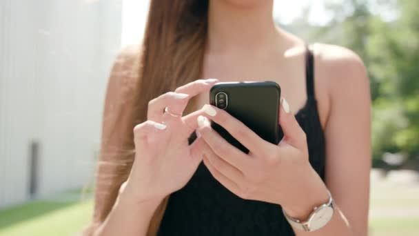 Giovane signora utilizzando un telefono in città mentre si cammina — Video Stock