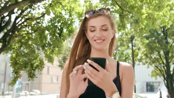 Молода леді використовує телефон у місті під час ходьби — стокове відео