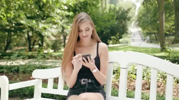 Giovane signora seduta sulla panchina e utilizzando un telefono — Video Stock