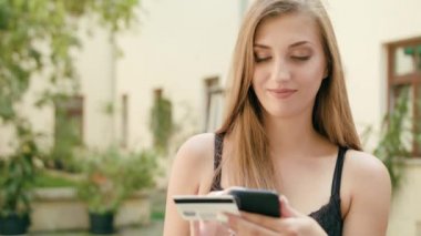 Genç bayan bir telefonu kullanarak ve kredi kartı tutan