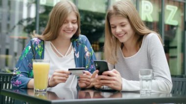 Bir telefonu kullanarak ve kredi kartı tutan genç bayanlar