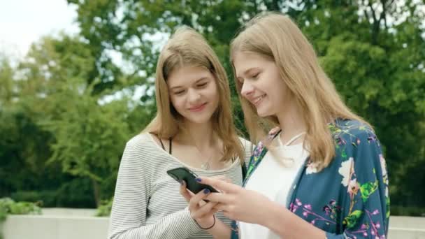 Señoras jóvenes usando un teléfono en la ciudad — Vídeos de Stock