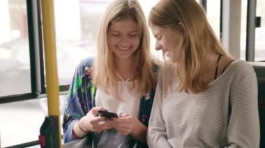 Genç bayanlar bir otobüste bir telefon kullanma