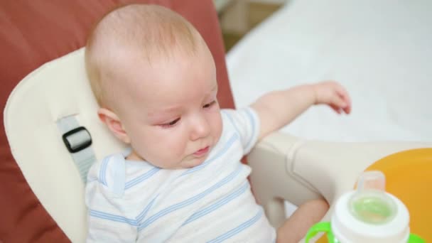 Bebé lindo bebiendo en la silla en casa — Vídeos de Stock